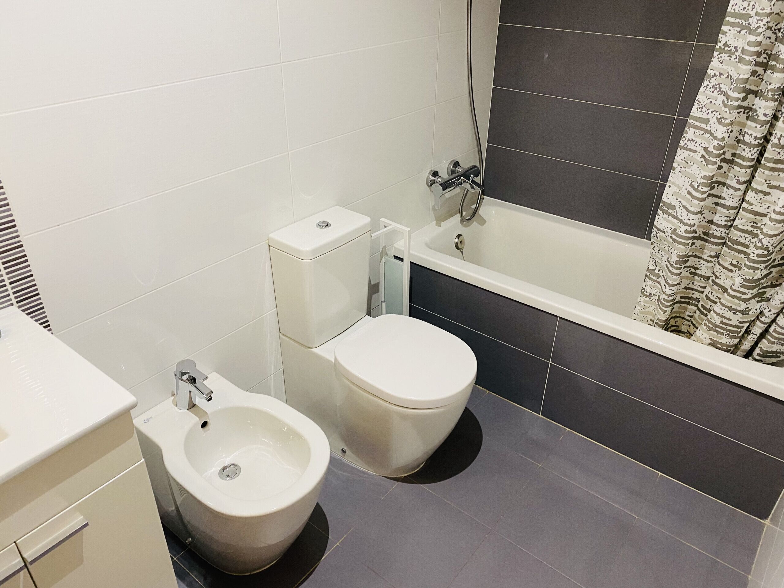A bathroom with a toilet, bidet, and bathtub.