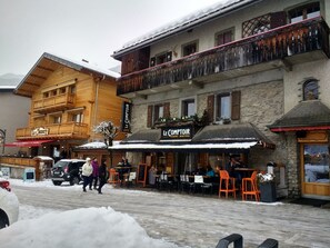 A restaurant with outdoor seating, a stone facade, and a wooden upper floor. - Modern Luxury Apartment in Châtel, only 150m from Lifts and Resort Centre. (Châtel)