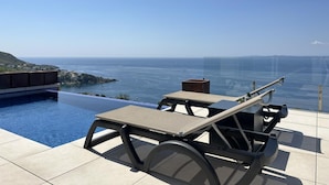 Un espace piscine aménagé sur le toit, offrant une vue dégagée sur la mer et le paysage lointain.