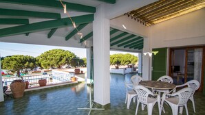A covered outdoor area with a tiled floor, white chairs, and a round table. - Holiday home- Puerto (Roses)