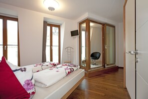 Ein Schlafzimmer mit Bett, Fernseher, Kleiderschrank und Spiegel.