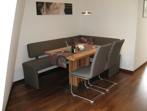 A modern dining area with a wooden table, grey upholstered chairs, a bench, and a small table lamp.