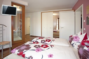 A bedroom with a bed, a TV, a wardrobe, and a mirror.