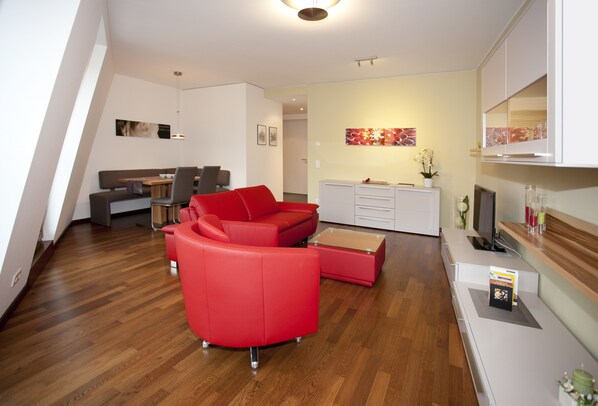 A modern living room with a red sofa, a wooden coffee table, and a white cabinet.