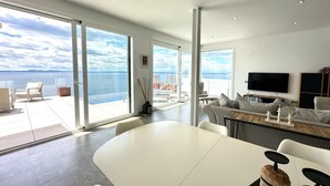 Un salon moderne avec une grande table blanche, des canapés à rayures et un téléviseur à écran plat.