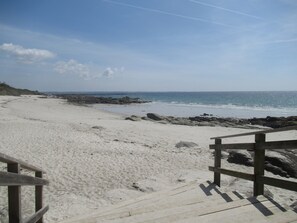 A sandy beach with a wooden walkway leading to the water.