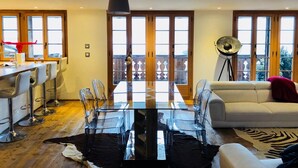 Un salón espacioso con una mesa de comedor de vidrio, un sofá y un amplio ventanal con vistas al balcón.