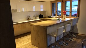Una cocina moderna con una isla de madera, taburetes de bar y un ventanal amplio.