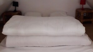 Et soveværelse med en stor seng, to sengeborde og et skråt loft.