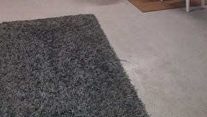 Et værelse med dør i træ, en rød stol, et bord med en potteplante og billeder i rammer på væggen.