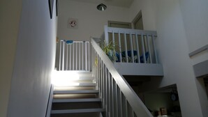 A staircase with white railings and a potted plant on the landing.