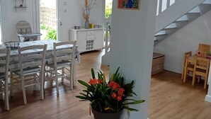 A spacious living area with a dining table, chairs, a potted plant, and a staircase.