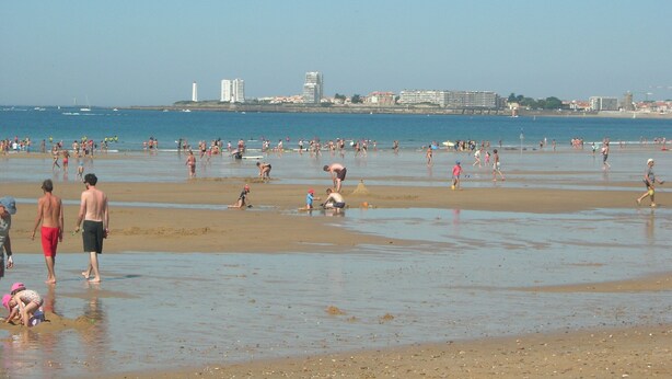 A crowded beach with people engaging in various activities.