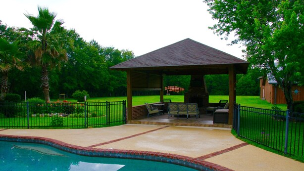 A covered patio area with a pool, surrounded by a fence and greenery. - Relaxing getaway in a peaceful spacious setting (Long Beach)
