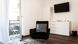 A modern living room with a black chair, a white wardrobe, and a flat-screen TV on the wall. - HOMY BnB (Empoli)