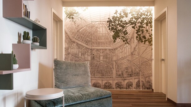 A modern interior with a cozy grey sofa, a small round table, and a wall with a large botanical mural. - HOMY BnB (Empoli)