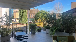A covered outdoor seating area with tables and chairs, surrounded by potted plants and trees. - HOMY BnB (Empoli)