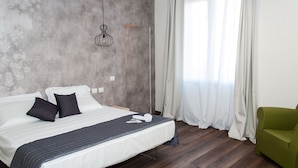 A hotel room with a large bed, a green armchair, and a view of the outdoors through sheer curtains. - HOMY BnB (Empoli)