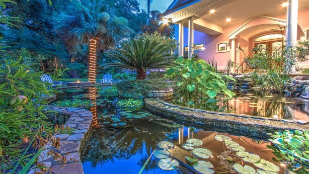 A serene garden with a pond, stone pathways, and lush greenery.