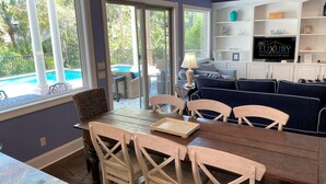 A dining area with a pool view, a TV, and a cozy seating area.