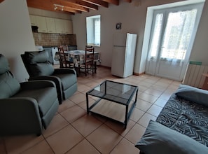 A living room with a glass coffee table, two sofas, a dining table with chairs, and a kitchen in the background. - The stable, quiet house in the bay of Dournenez (Quéménéven)