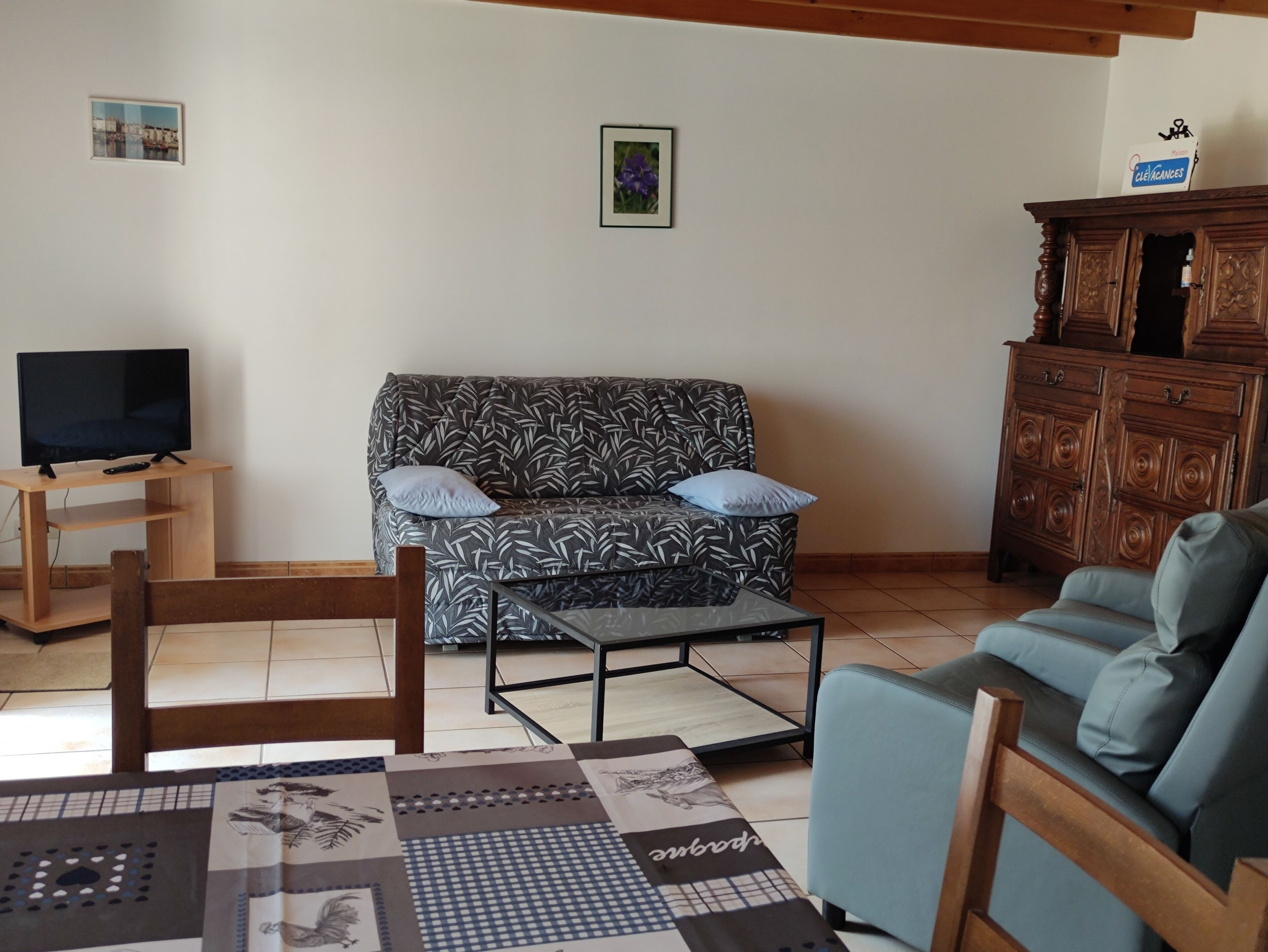 A living room with a sofa, a television, a wooden cabinet, and a patterned rug.