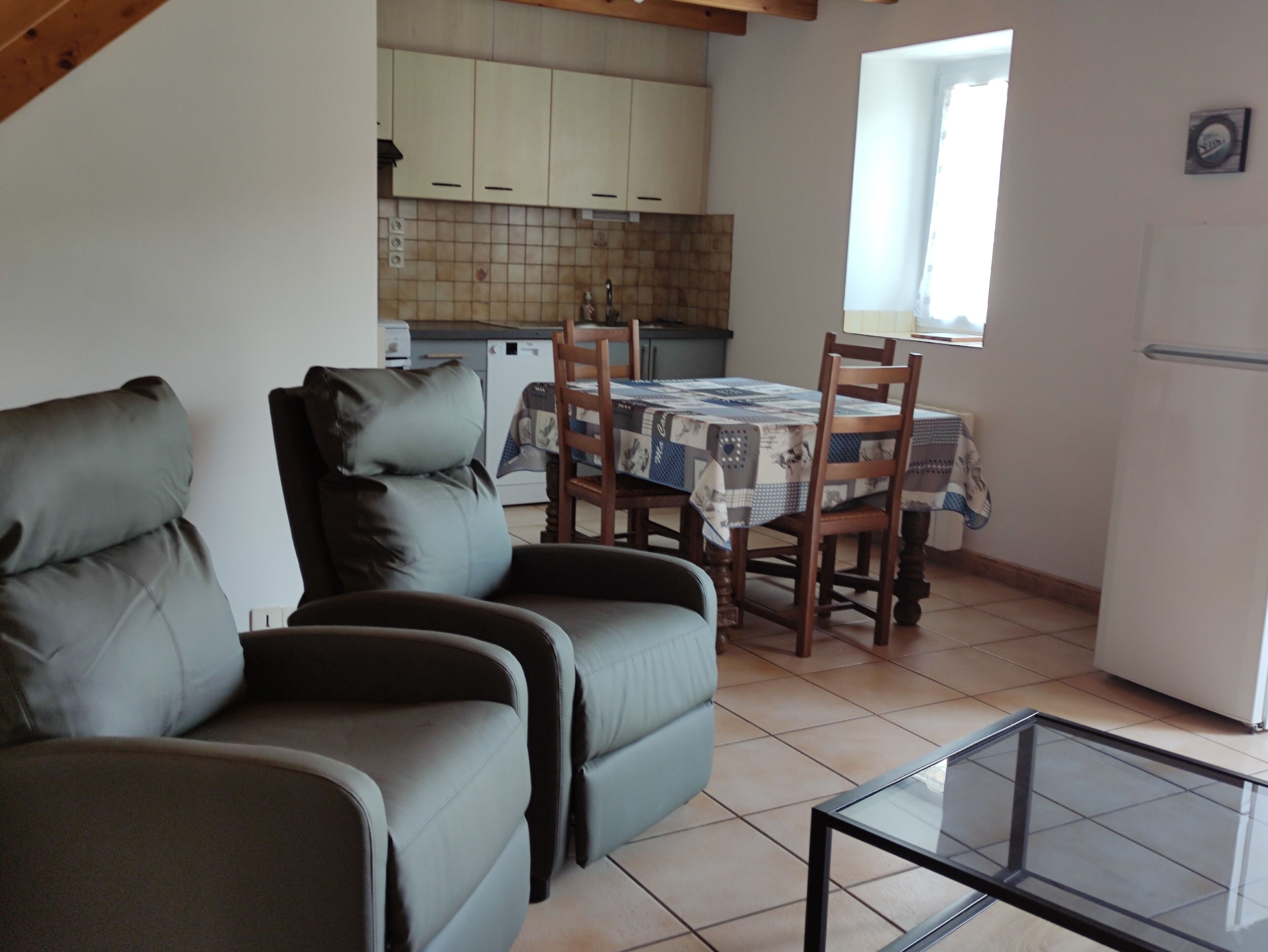 Un espace de vie compact comprenant un canapé, une table à manger avec des chaises, un coin cuisine et une fenêtre.