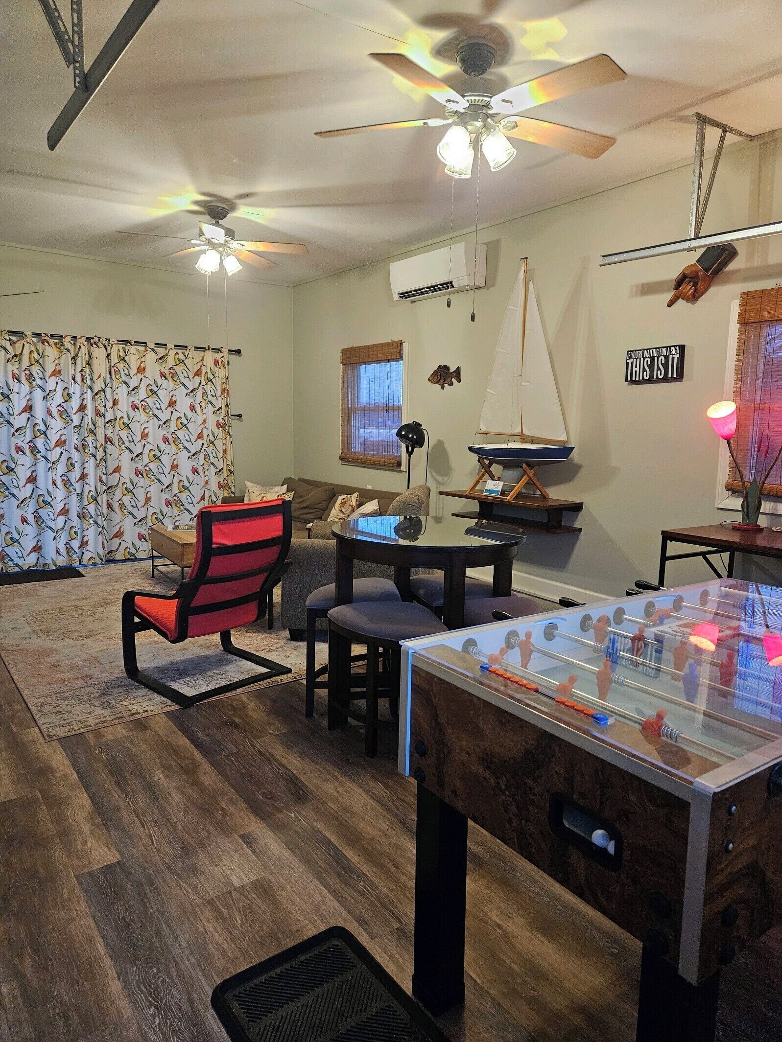 Un salon chaleureux avec une table de baby-foot, un ventilateur de plafond et une décoration sur le thème de la voile.