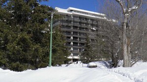 A multi-story parking garage with a modern design, surrounded by trees and covered in snow. - Cozy Studio in Chantemerle - Sleeps 4, Parking, Balcony, 2 Stars (Saint-Chaffrey)