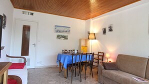 A cozy room with a wooden ceiling, a dining table with chairs, a sofa, and a lamp. - Cozy Studio in Chantemerle - Sleeps 4, Parking, Balcony, 2 Stars (Saint-Chaffrey)