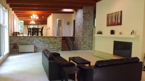 Ein Wohnzimmer mit Kamin, Fernseher und einer Couch. Eine Treppe führt in einen anderen Raum.