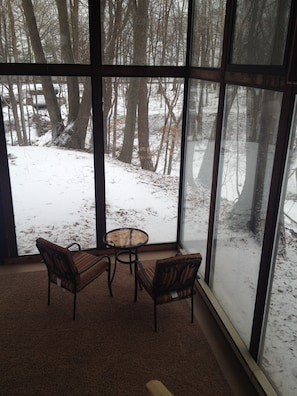 Relax in a serene space with a large window offering a view of the surrounding forest and snow-covered ground.