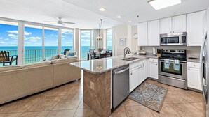 A kitchen with a large island, white cabinets, stainless steel appliances, and a view of the ocean. - West Corner w/Massive Balcony and Spectacular Gulf-Front Views! (Gulf Shores)
