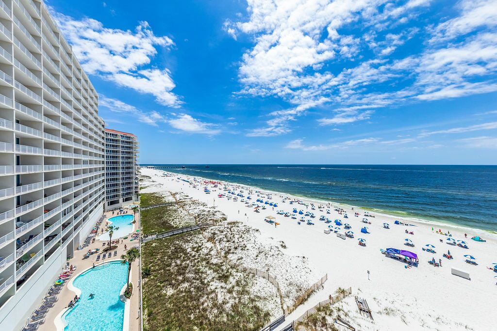 A hotel with a pool, beach, and ocean view.
