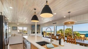 Una cocina moderna con armarios de madera, encimera blanca e iluminación colgante.