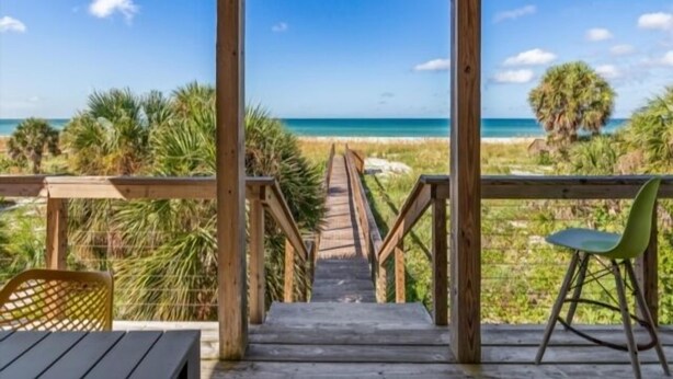 Una terraza de madera con vista a la playa y al océano.