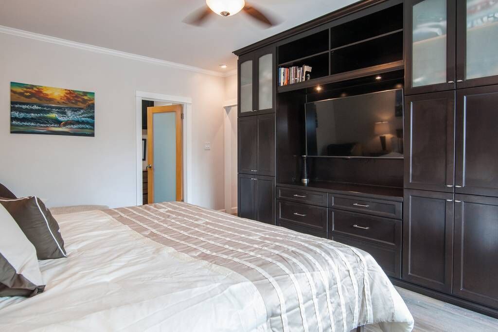 Une chambre avec un grand lit, une armoire en bois foncé et un ventilateur de plafond.
