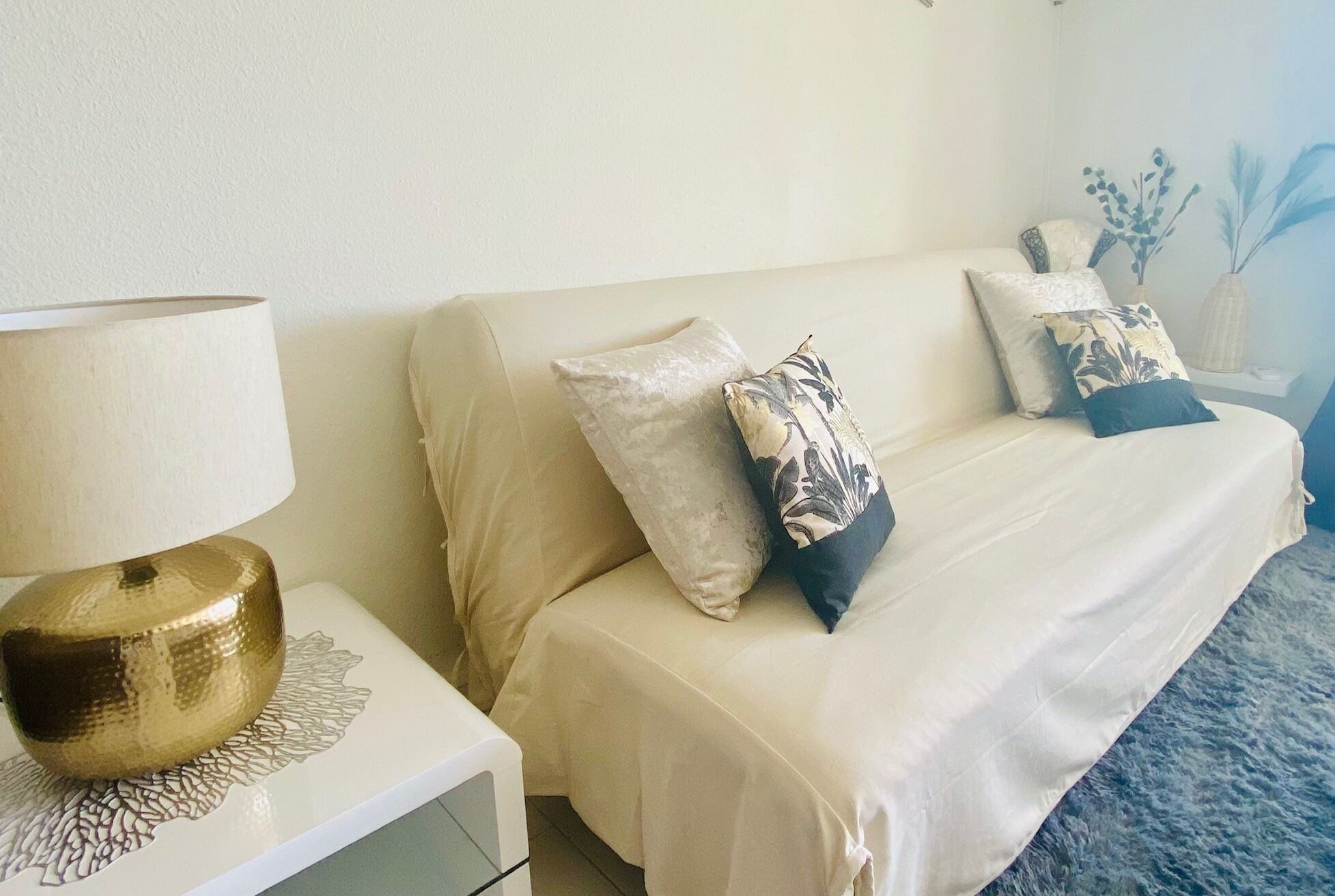 A bedroom with a bed, a nightstand, a lamp, and decorative pillows.