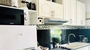 Cocina moderna con armarios blancos, horno empotrado, lavamanos y encimera con tostadora y licuadora.