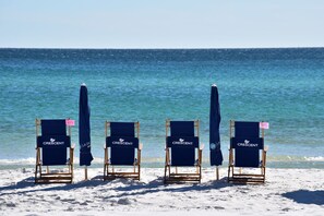 Four beach chairs with 'Crescent' branding and numbered signs, arranged on a sandy beach with the ocean in the background.