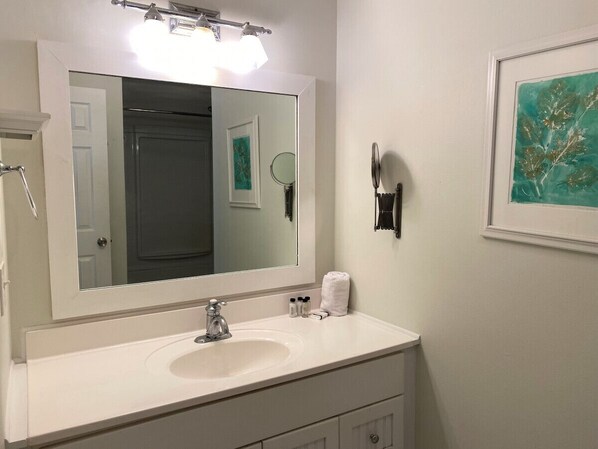 A bathroom with a white vanity, a large mirror, a sink, and a framed artwork on the wall. - 839 Marsh Dunes - Community Pool - Golf Cart Included (Saint Helena Island)