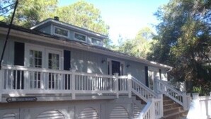 A two-story house with a white exterior, a front porch, and a staircase leading to the upper floor. - 839 Marsh Dunes - Community Pool - Golf Cart Included (Saint Helena Island)