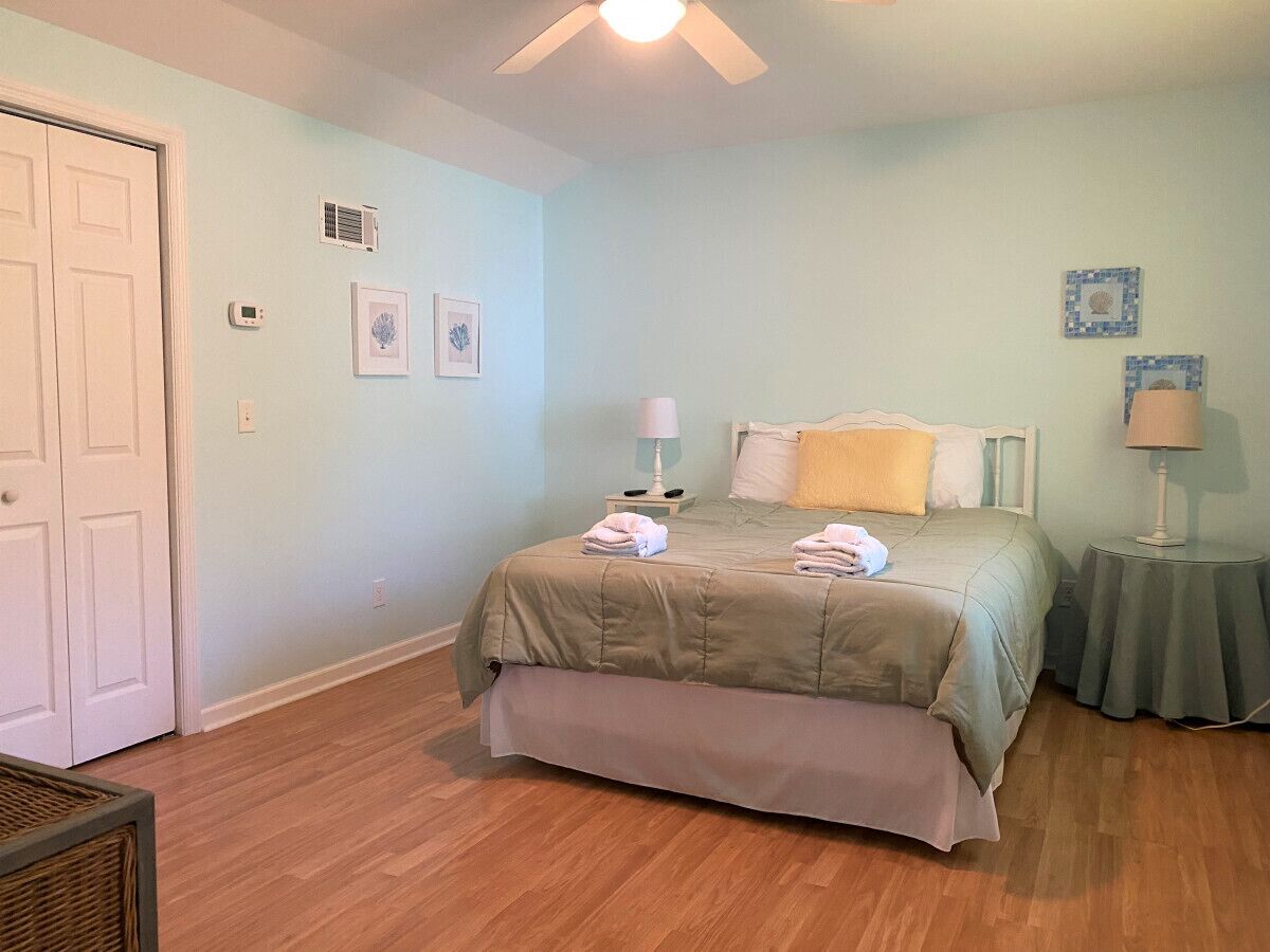 A bedroom with a bed, bedside tables, a ceiling fan, and a door.