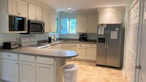 A kitchen with white cabinetry, a stainless steel refrigerator, a microwave, a toaster, and a sink. - 839 Marsh Dunes - Community Pool - Golf Cart Included (Saint Helena Island)