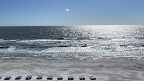 Ein Strand mit blauem Himmel, Wellen und einer Reihe von Liegestühlen.