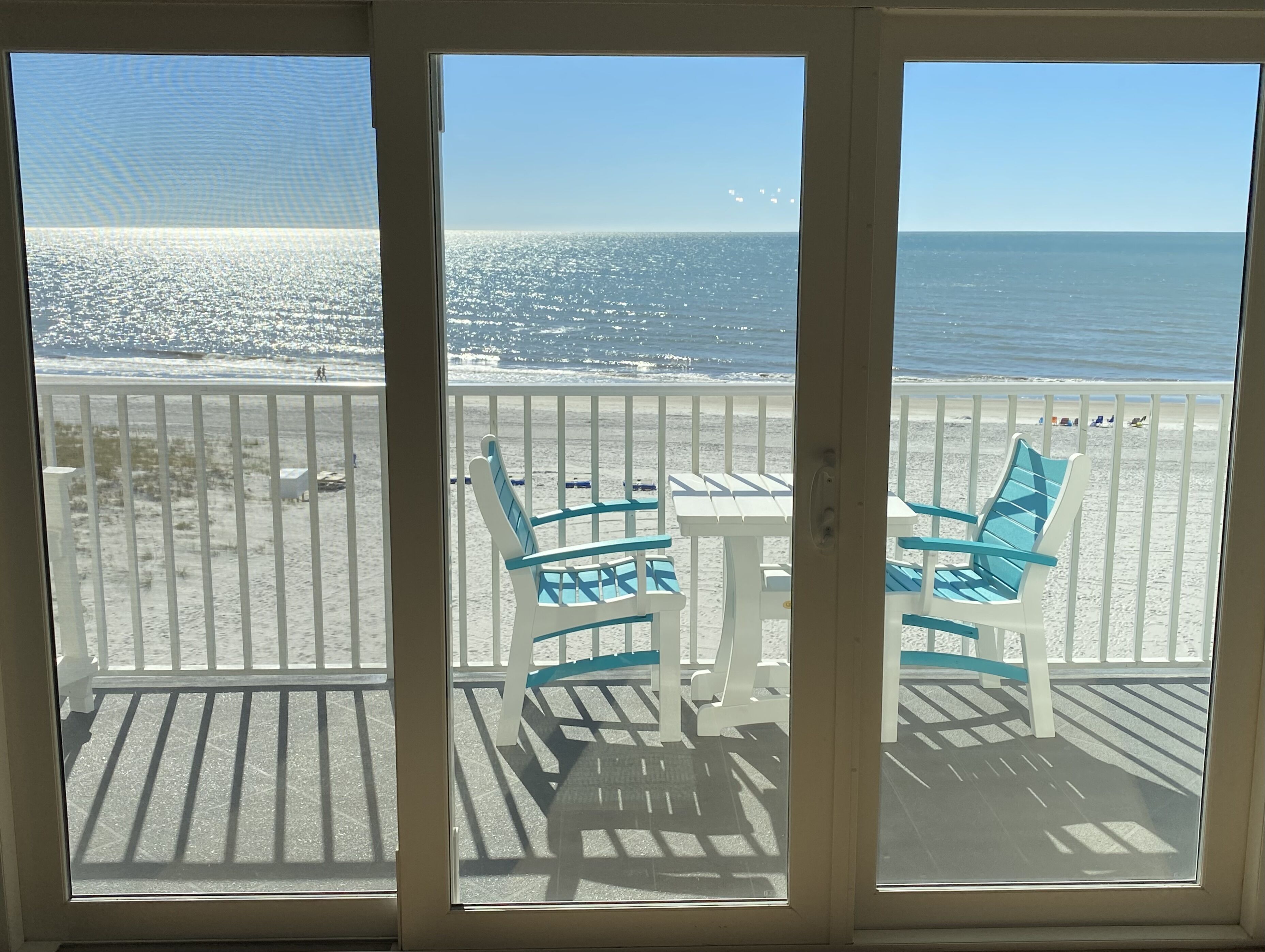 A balcony with a view of the beach and ocean.