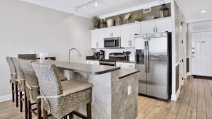 Una cocina moderna con una isla central, electrodomésticos de acero inoxidable y una zona de bar con asientos.