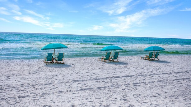 A beach with three turquoise umbrellas and matching lounge chairs facing the ocean. - BEACHFRONT BUILDING l PRIVATE BEACH l GULF GLIMPSE l SEASONAL BEACH SETUP (Santa Rosa Beach)