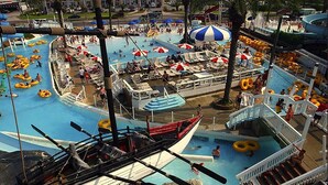 Un parco acquatico con diverse piscine, pedalò e zone relax con ombrelloni.