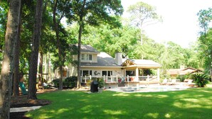 A large house with a covered porch, a lawn, and trees.
